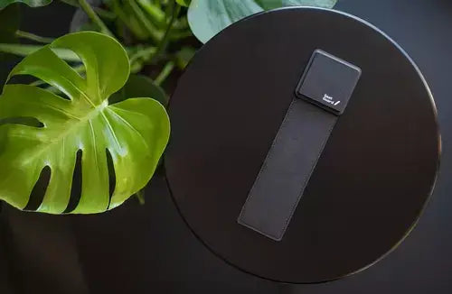 Black ErgoFinland Seat Guard microbreaks on a table with green leaves for enhanced sitting comfort.